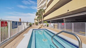 A swimming pool with a metal ladder, surrounded by a white fence with multiple signs, including a no smoking sign. - Emerald Isle 1905 - JUST COMPLETELY RENOVATED! Beach chair service included! (Panama City Beach)