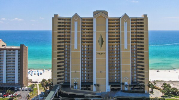 A high-rise hotel with multiple balconies, a beach view, and a parking area. - Emerald Isle 1905 - JUST COMPLETELY RENOVATED! Beach chair service included! (Panama City Beach)