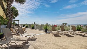 A rooftop patio with lounge chairs and tables, overlooking a beach. - Emerald Isle 1905 - JUST COMPLETELY RENOVATED! Beach chair service included! (Panama City Beach)