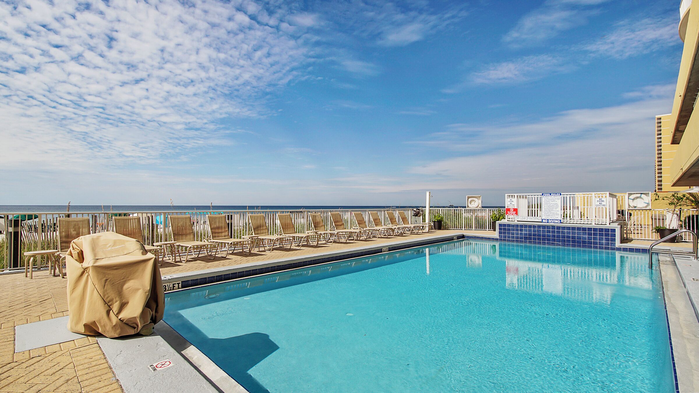 Ein Poolbereich mit Liegestühlen und Blick aufs Meer.