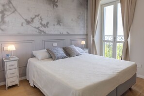 Ein Schlafzimmer mit einem Bett, Nachttischen, einer Lampe und einem Fenster mit Vorhängen.