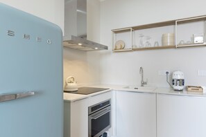 Eine Küche mit einem blauen Kühlschrank, einem Wasserkocher, einer Kaffeemaschine und einem Einbauofen.
