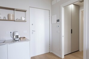 Eine moderne Küche mit Kaffeemaschine, einer weißen Tür und einem Gang zu einem weiteren Raum.