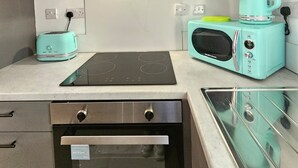 A compact kitchen with a built-in oven, a toaster, a microwave, and a gas stove. - Luxury 2Bedroom Near Station + Bike (Cambridge)