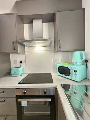 A compact kitchen with a built-in oven, a toaster, a microwave, and a gas stove. - Luxury 2Bedroom Near Station + Bike (Cambridge)