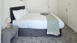 A bedroom with a bed, bedside table, lamp, and a door. - Luxury 2Bedroom Near Station + Bike (Cambridge)