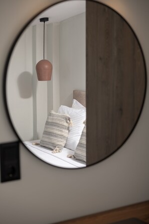 A round mirror reflecting a bed with pillows and a hanging light fixture. - Strovilla Gaia 3 Luxury Private Beachfront Villas (Psakoudia)