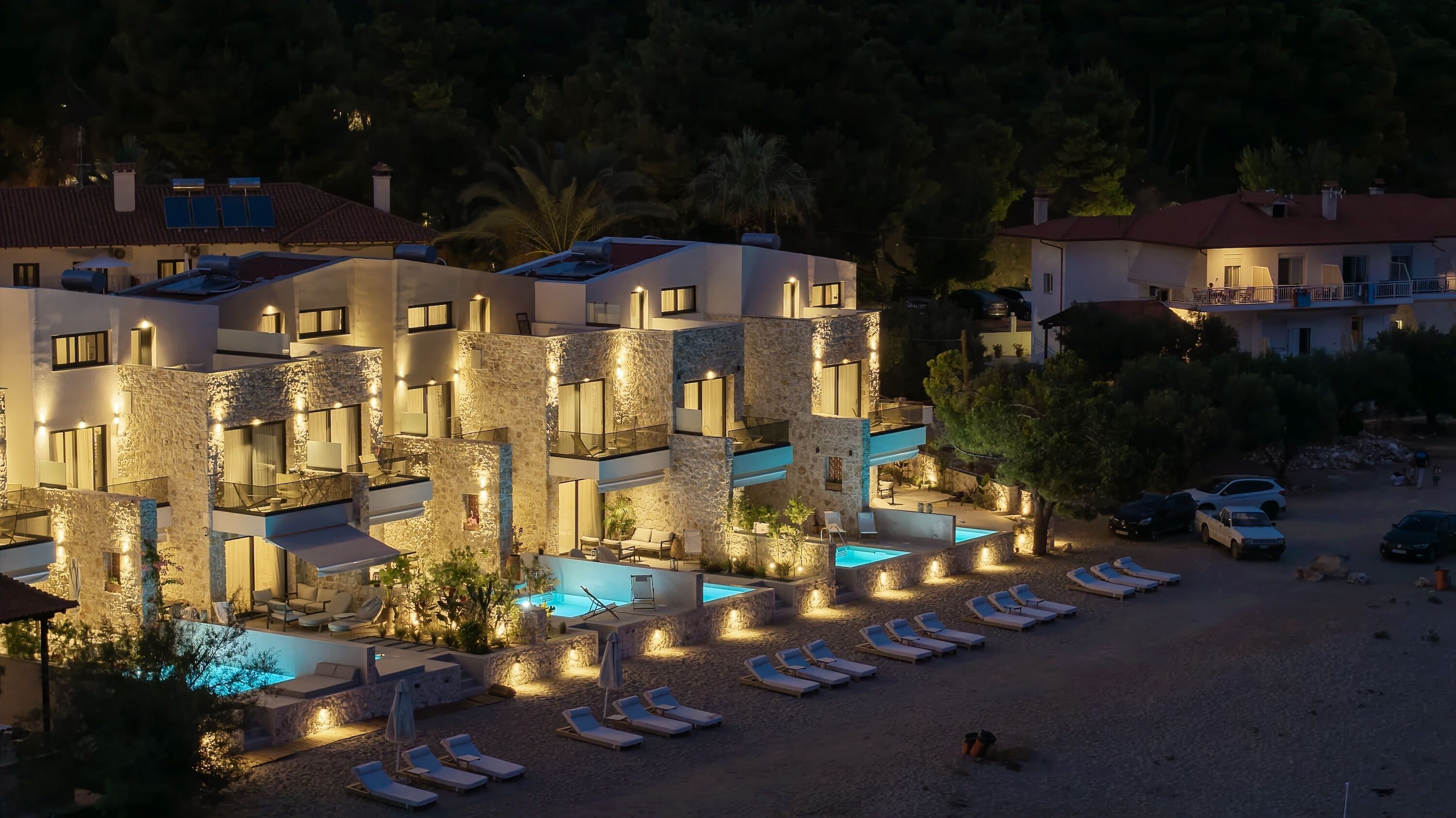 A multi-story hotel with stone facades, outdoor pools, and sun loungers.