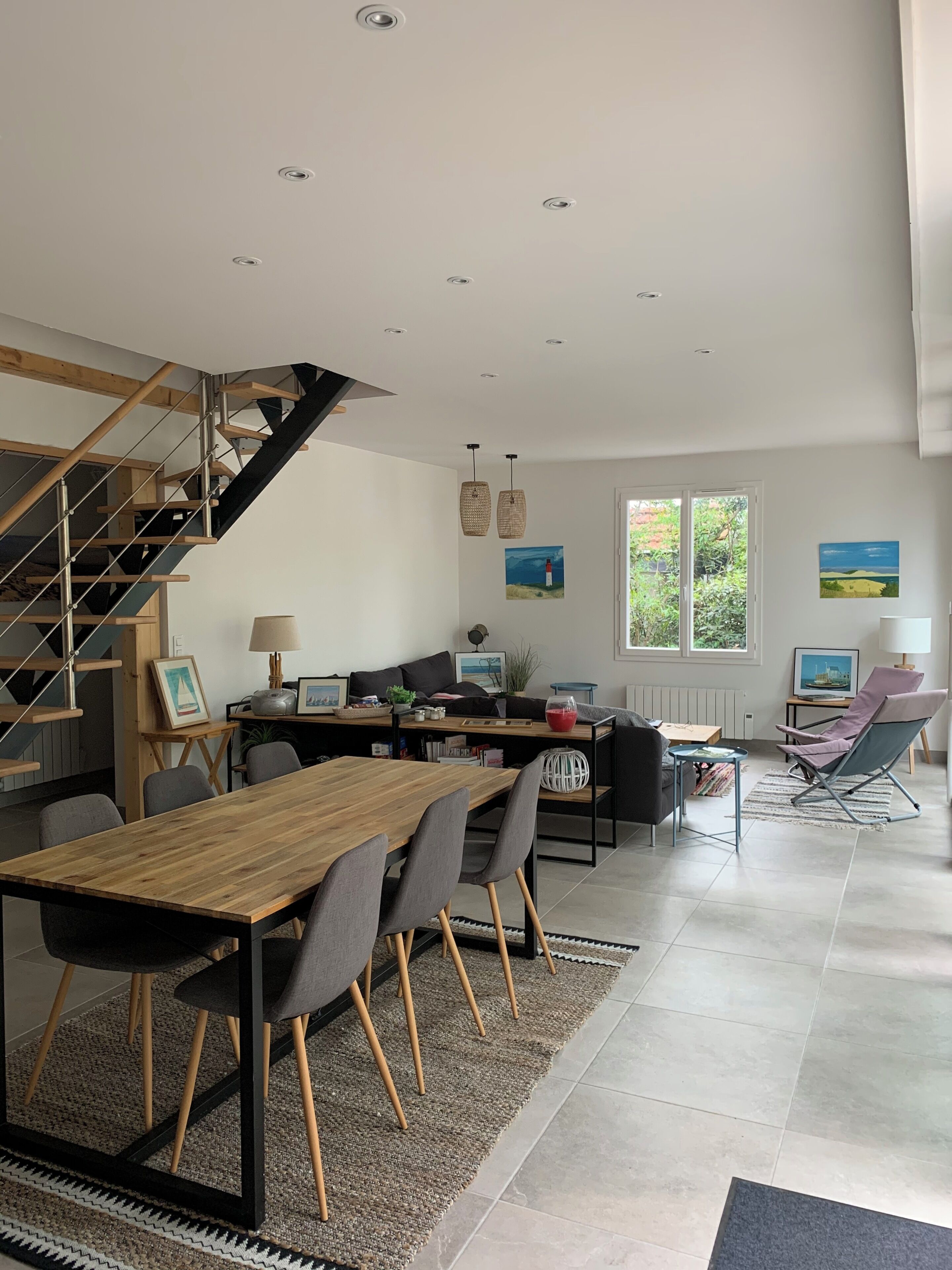 A modern living space with a staircase, dining area, and seating.