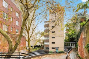 Ein schmaler Stadtpfad, an einer Seite ein Backsteingebäude und auf der anderen eine moderne Struktur.