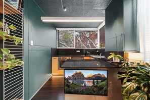 Eine moderne Küche mit integrierter Kochinsel, Edelstahlgeräten und einem großen Fenster mit Jalousien.