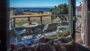 A deck with outdoor furniture, a table, and a view of the ocean. - Moon Shadow (TOT ID #2164): 2  BR, 2  BA House in The Sea Ranch, Sleeps 4 (The Sea Ranch)
