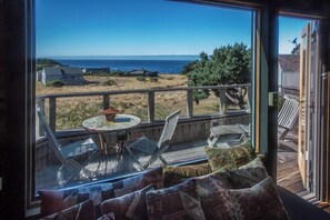 A deck with outdoor furniture, a table, and a view of the ocean. - Moon Shadow (TOT ID #2164): 2  BR, 2  BA House in The Sea Ranch, Sleeps 4 (The Sea Ranch)