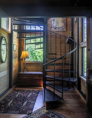 A spiral staircase with a metal railing, wooden walls, and a window with a view of greenery. - Moon Shadow (TOT ID #2164): 2  BR, 2  BA House in The Sea Ranch, Sleeps 4 (The Sea Ranch)