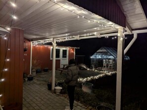 A covered outdoor area with a wooden structure, potted plants, and a greenhouse. - 5 Star Holiday Home in Jaegerspris (Jægerspris)