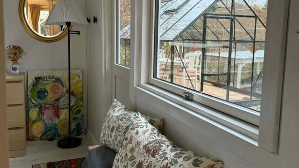 A room with a large window, a bench, a lamp, a painting, and a mirror. - 5 Star Holiday Home in Jaegerspris (Jægerspris)