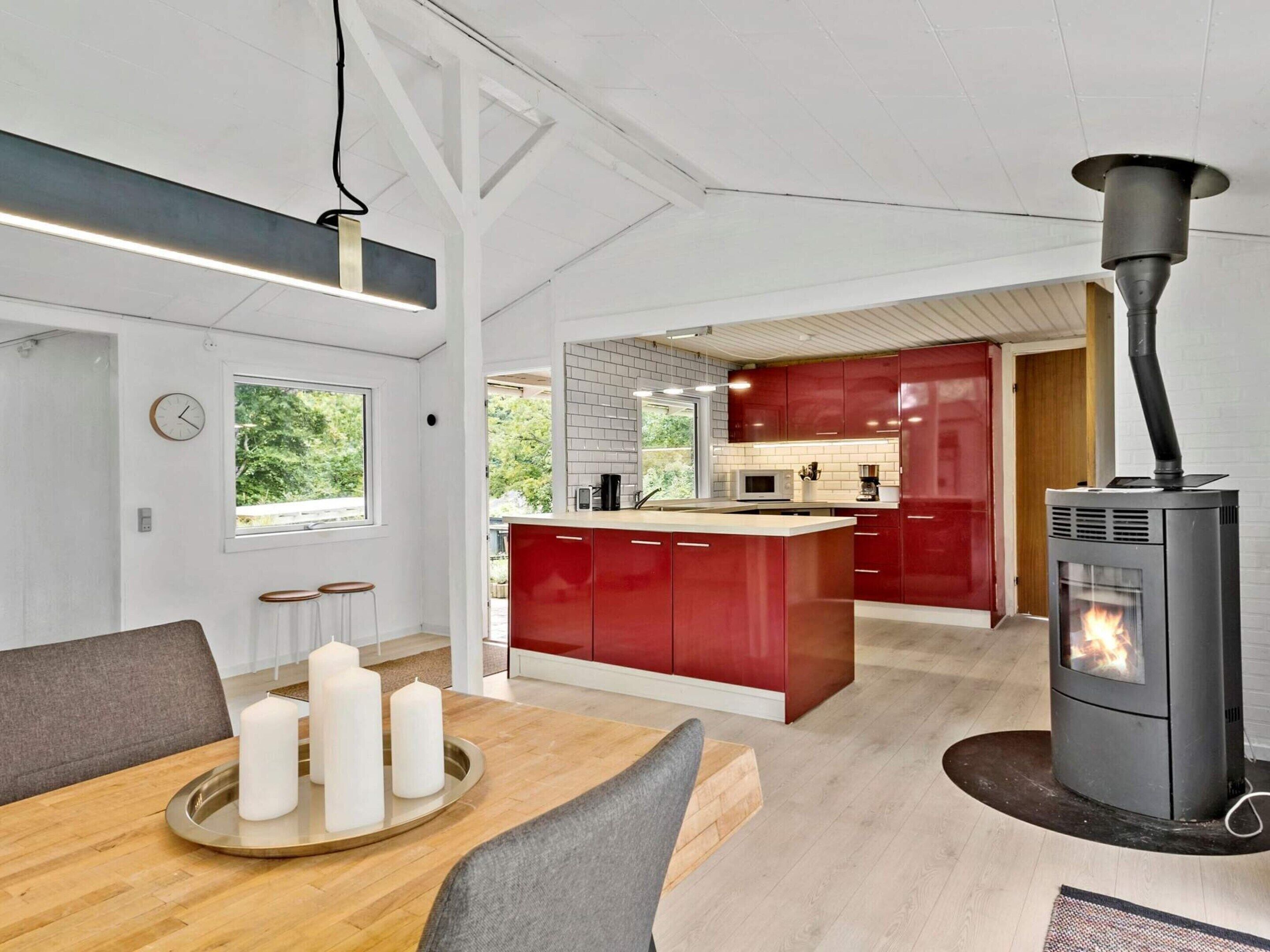 Une cuisine moderne avec des meubles de couleur rouge, un îlot central et un poêle à bois.