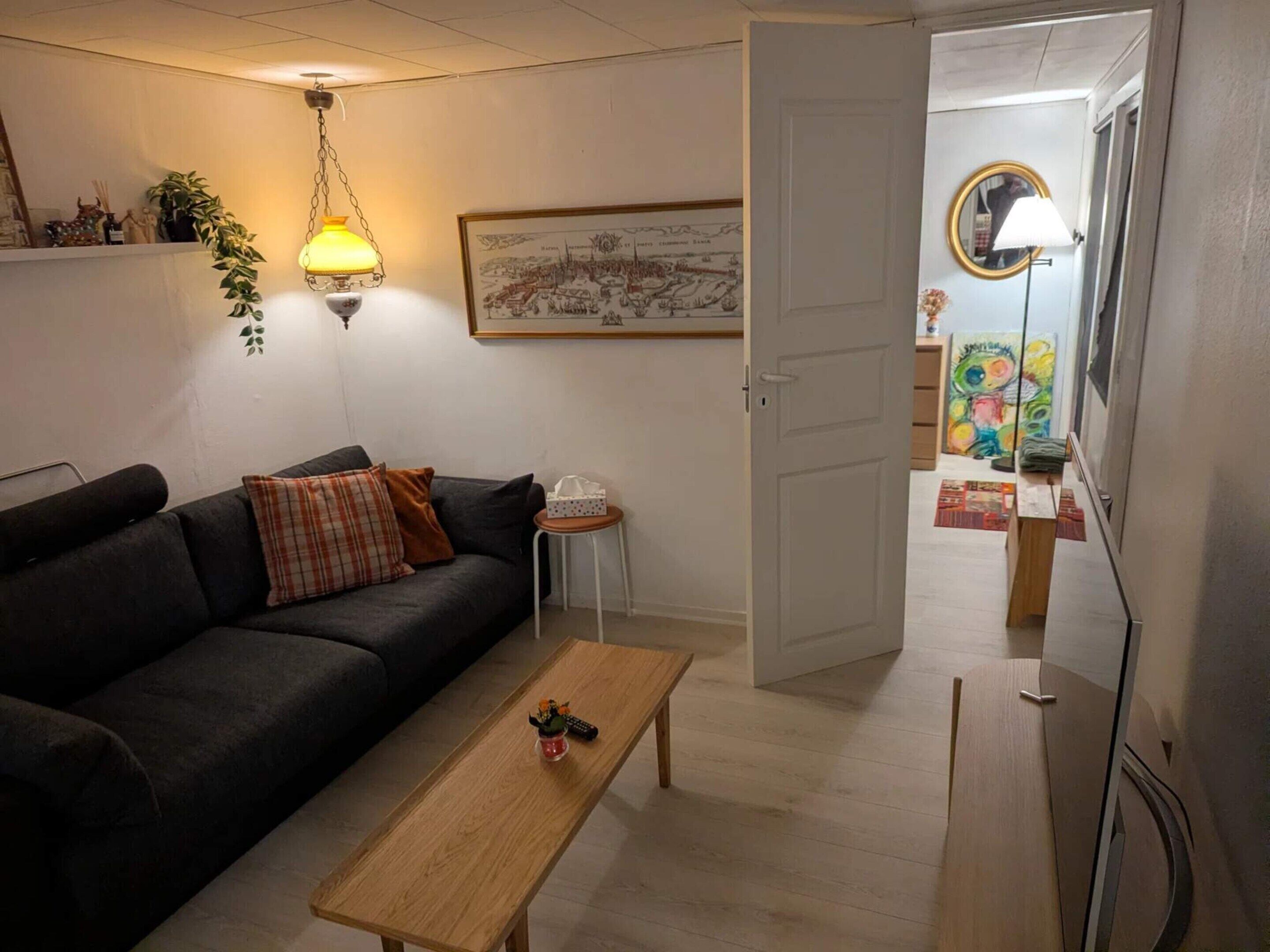 Uma sala de estar com um sofá, uma mesa de centro, um abajur e um quadro na parede.