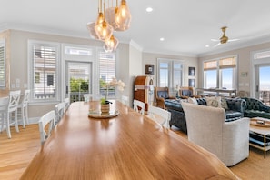 Un amplio espacio de sala con una mesa de comedor de madera, asientos cómodos y grandes ventanales con vistas.