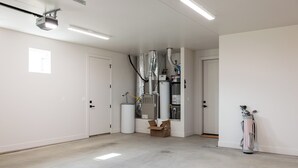 Een ruime kamer met een groot, centraal verwarmingssysteem, een deur en een golftas tegen de muur.