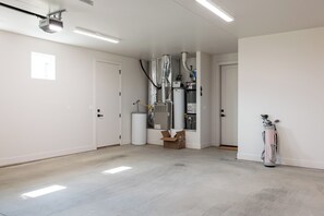 A spacious room with a large, central heating unit, a door, and a golf bag against the wall. - Serenity on the 6th: 4  BR, 4  BA House in St. George, Sleeps 10 (St. George)