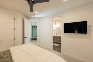 A bedroom with a bed, a ceiling fan, a TV, and a bathroom with a sink and mirror. - Serenity on the 6th: 4  BR, 4  BA House in St. George, Sleeps 10 (St. George)