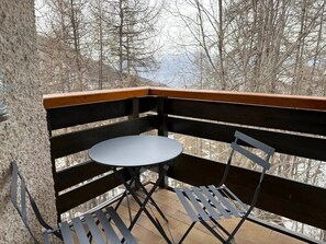 Ein Balkon mit einem kleinen runden Tisch und zwei Stühlen.