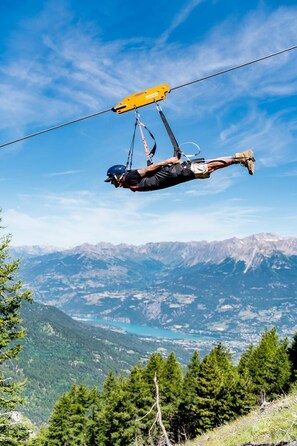 Eine Person schwebt in einer Schlinge, im Hintergrund eine gebirgige Landschaft.