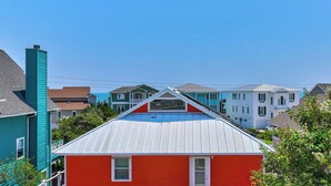 Un quartier résidentiel où se trouvent des maisons de différentes couleurs et de styles architecturaux variés, dont une maison rouge remarquable avec un toit blanc.
