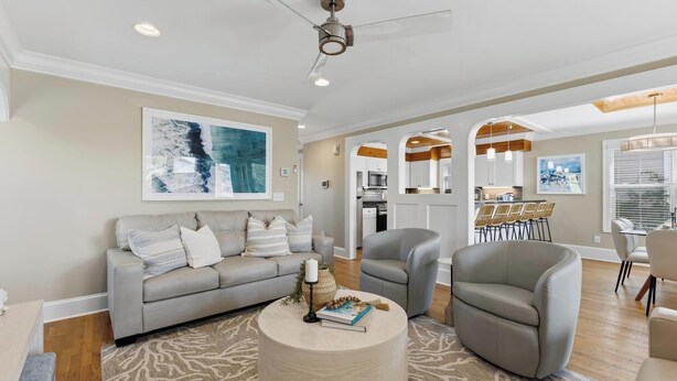 Un salon moderne avec un canapé gris, des fauteuils, une table basse et un ventilateur de plafond.