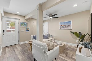 A spacious living room with a white sofa, a coffee table, and a ceiling fan. - 🌊Sandman by the Sea - Pet Friendly 4 Bedroom Home with Spacious Decks🏖️ (Kure Beach)