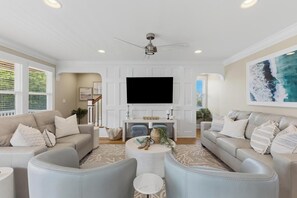 Ein modernes Wohnzimmer mit Flachbildfernseher, zwei Sofas, einem Couchtisch und Deckenventilator.