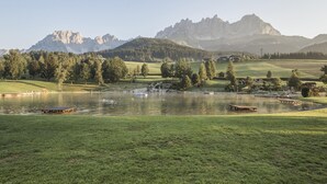 Ein See mit Booten, eine Holzsteganlage und eine Bergkulisse im Hintergrund.