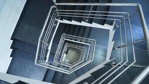 Eine Wendeltreppe mit Metallgeländern und einem dunklen Boden.