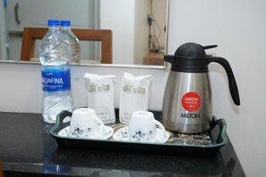 A tray with a thermos, a bottle of water, and two cups with tea bags.