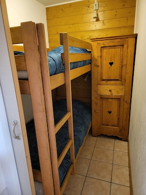 A bunk bed with a wooden ladder, a small cabinet with a heart-shaped handle, and a tiled floor. - 3-star apartment at the base of the slopes, large terrace, 2 bedrooms (Les Deux Alpes)