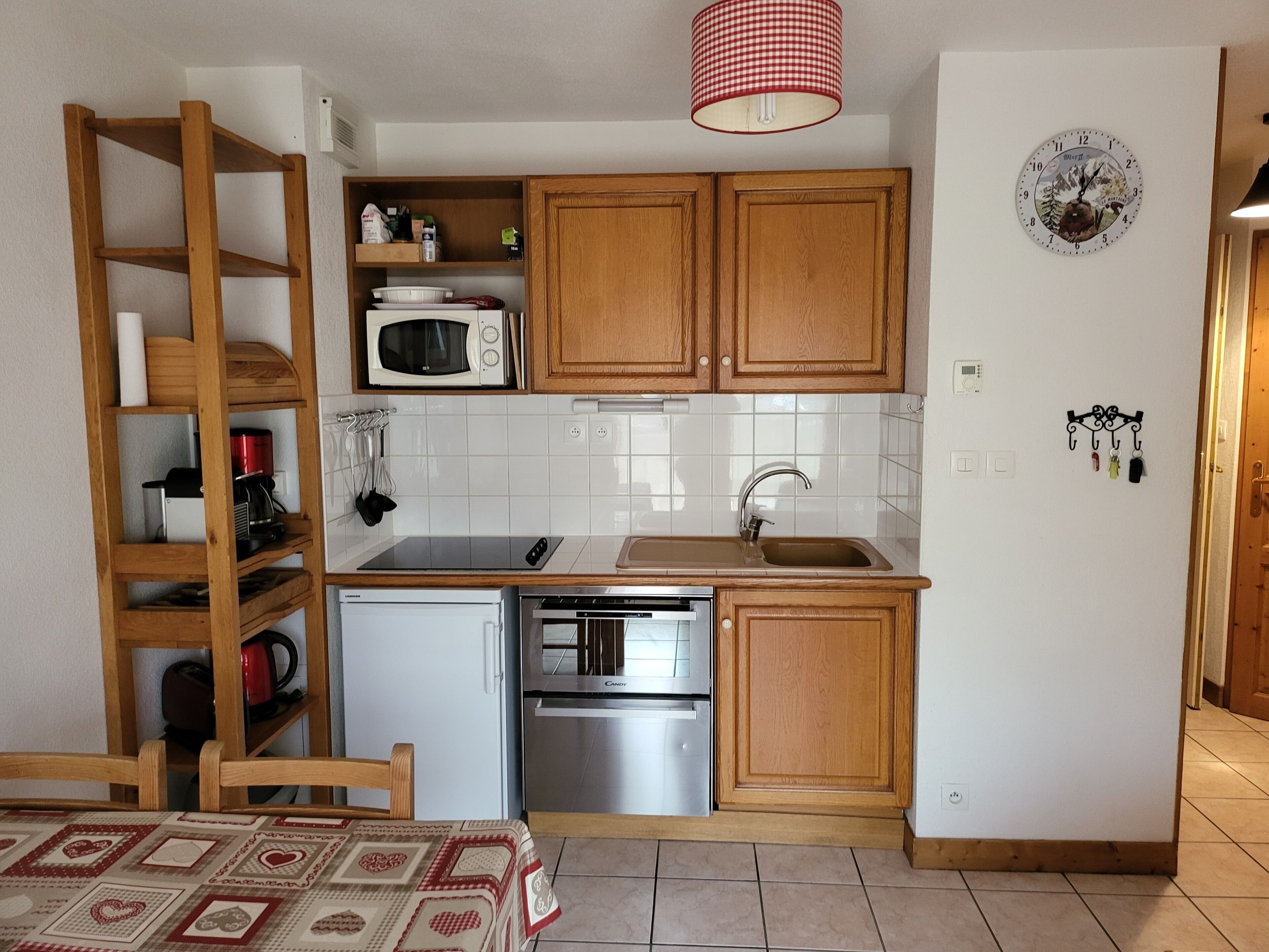 A compact kitchen with wooden cabinets, a microwave, a sink, and a refrigerator.