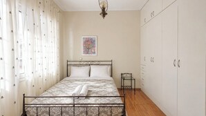 A bedroom with a bed, a wardrobe, a nightstand, and a hanging light fixture.
