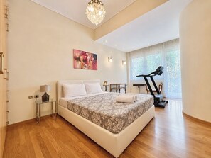 A bedroom with a large bed, a treadmill, and a window with a view.