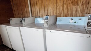 Une rangée d’appareils électroménagers blancs, probablement des machines à laver, dans une pièce en bois dotée d’un plafond en pente.