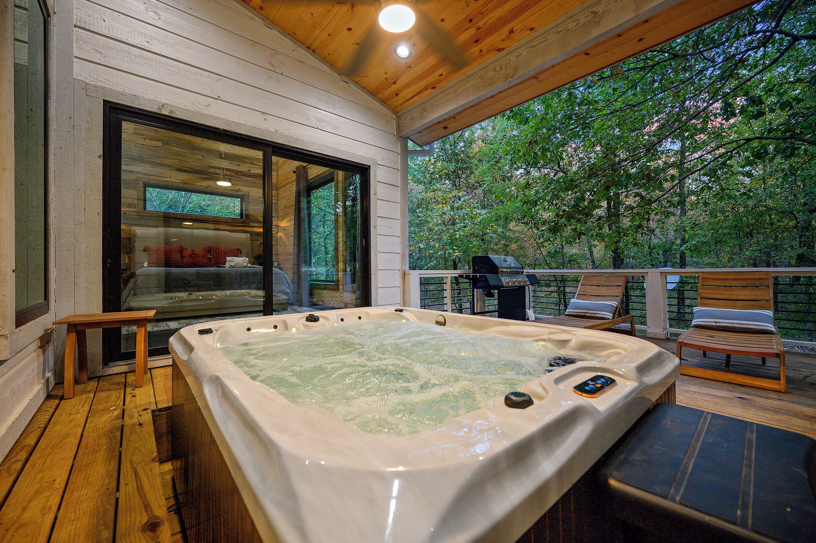 A hot tub on a wooden deck with a view of trees.