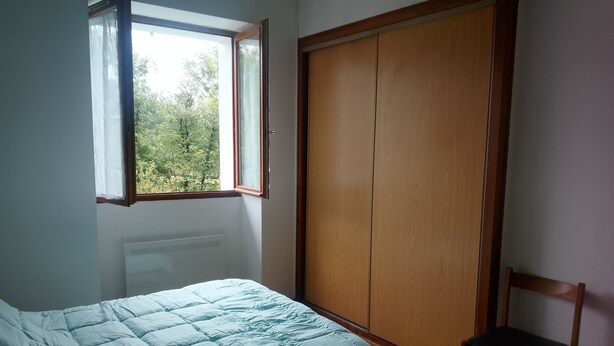 Quarto com uma cama, janela, guarda-roupa e uma cadeira.