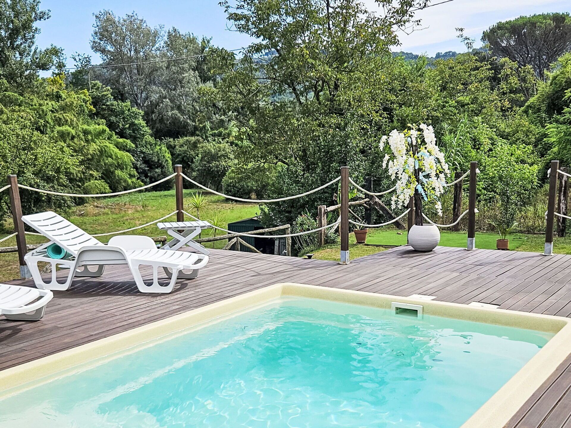 A pool area with lounge chairs and a wooden deck.