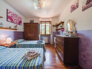 Ein Schlafzimmer mit zwei Betten, einem Schminktisch, einem Fenster und Bildern an den Wänden.
