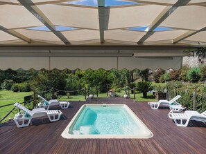 A hot tub with a wooden deck, surrounded by lounge chairs and a covered area with a view of a garden. - Stunning private villa for 6 guests with private pool, WIFI, TV, patio and pets allowed (Camaiore)