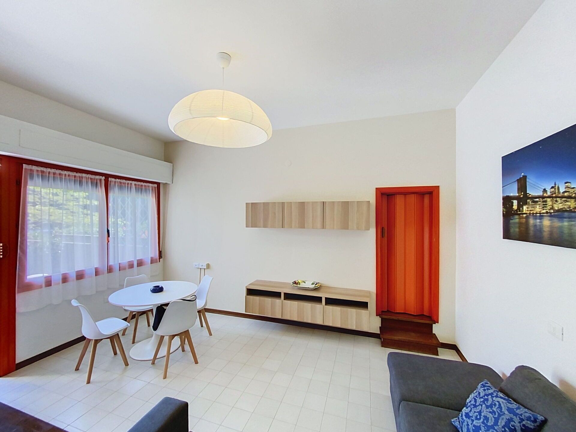 Ein modernes Wohnzimmer mit Essbereich, einer roten Tür und einem Stadtbildgemälde.