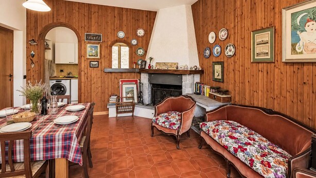 A cozy room with a fireplace, wooden walls, a dining table set for four, and a sofa. - Beautiful  villa for 5 guests with hot tub, WIFI, balcony, pets allowed and panoramic view (Rocca Sinibalda)