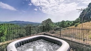 A hot tub surrounded by a metal fence, with a view of distant mountains and greenery. - Beautiful  villa for 5 guests with hot tub, WIFI, balcony, pets allowed and panoramic view (Rocca Sinibalda)