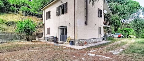 A two-story house with a stone foundation, a front door, and a small porch area.