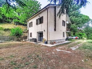 Ein zweistöckiges Haus mit Steinfassade, einer Haustür und einem kleinen Vorbereich.